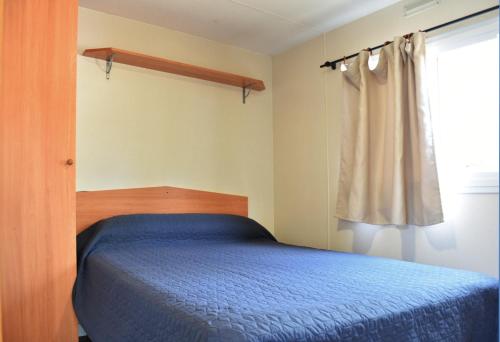 a bedroom with a blue bed and a window at Camping Bungalows Sol D´Or in Peniscola