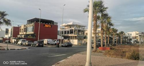 eine Stadtstraße mit Autos, die vor den Gebäuden geparkt sind in der Unterkunft Appartement Proche plage Bouznika Bouznika in Bouznika