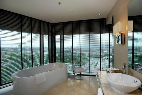 uma casa de banho com 2 lavatórios, uma banheira e janelas em Grand Ankara Hotel Convention Center em Ancara