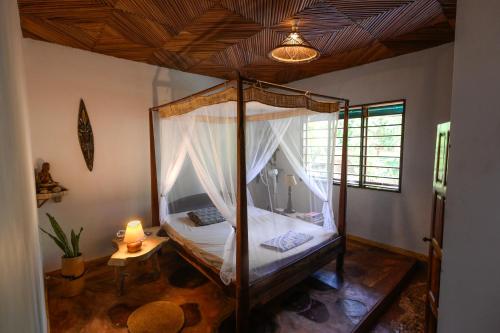 a bedroom with a canopy bed in a room at Shambala Madagascar: Beachfront Lodge And Adventures in Ambolobozo