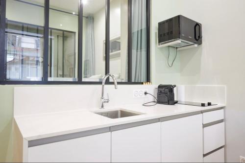 Il comprend une cuisine avec un évier et une télévision murale. dans l'établissement VERY CHARMING AND COSY FLAT, center of Paris, à Paris