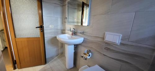 y baño con lavabo blanco y espejo. en Jon rooms, en Himare