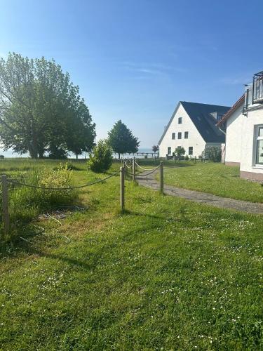 a fence in a field next to a white barn at App 14 Entspannen im Wellengang! in Dranske