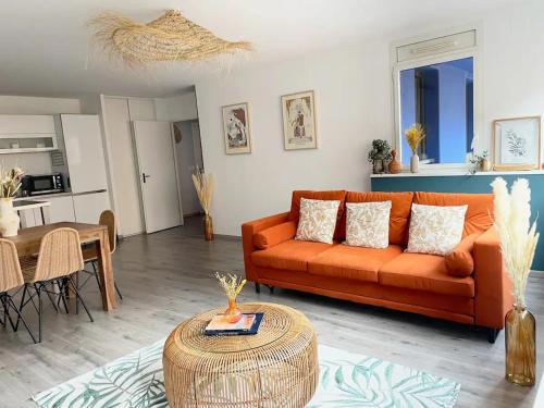 un salon avec un canapé orange et une table dans l'établissement Pénitents by Yumē, à Toulouse