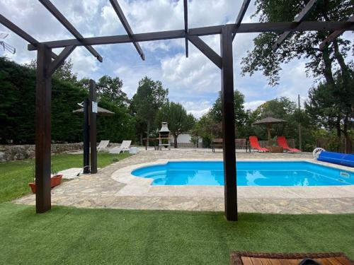 uma piscina com uma pérgola, uma mesa e uma mesa de piquenique em El Molino de Candelario em Candelario