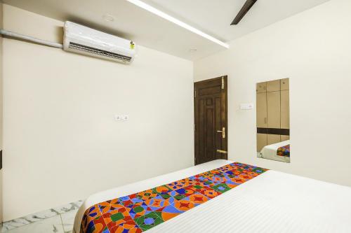 FabExpress 7 Hills Home Stay في تيروباتي: غرفة نوم مع سرير وبطانية ملونة