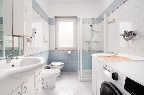 a white bathroom with a sink and a toilet at Casa Vacanza Cala Luna in Orosei