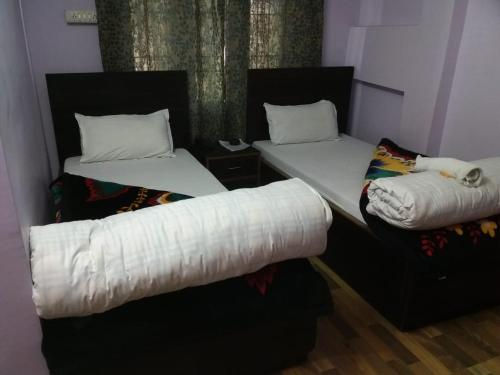 two beds in a room with white sheets at Menda-La in Tawang