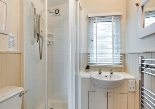 a white bathroom with a sink and a shower at Gulls Cry in Stoke Fleming