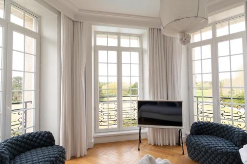a living room with two chairs and a flat screen tv at Les Garennes - Hôtel Spa Bénodet in Bénodet