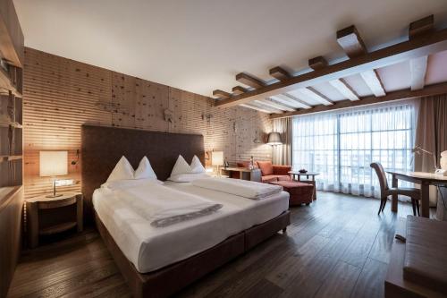 um quarto com uma cama grande e uma sala de estar em Adler Spa Resort Dolomiti em Ortisei