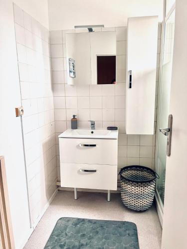 une salle de bain blanche avec un lavabo et un miroir dans l'établissement Maison de famille, à Lormont