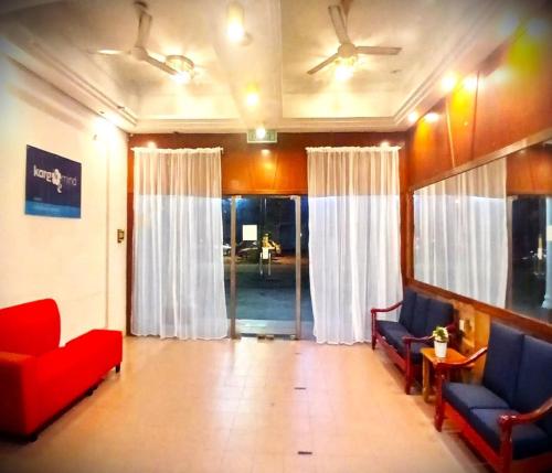 a waiting room with red chairs and white curtains at Alia Express Green Mango, Kota Bharu in Kota Bharu
