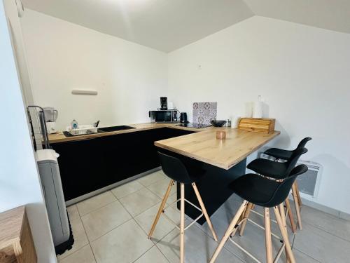 une cuisine avec une table en bois et deux chaises noires dans l'établissement Studio cosy à Concarneau, Plage à 3 min, à Concarneau