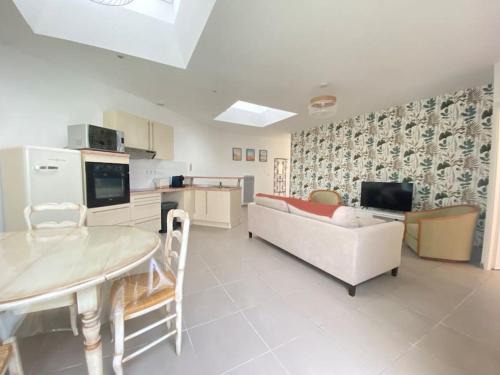 Il dispose d'une cuisine et d'un salon avec un canapé et une table. dans l'établissement Le Patio plain-pied face port, à Étaples