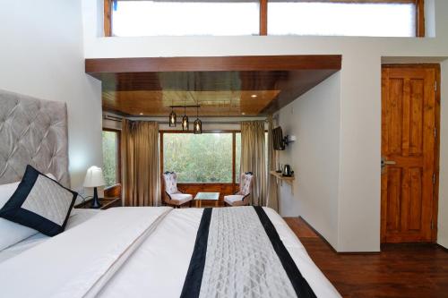a bedroom with a large bed and a large window at Thiksay Organic Resort in Ranbirpura