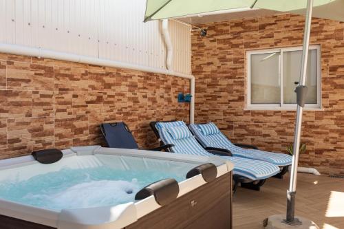 a hot tub with two chairs and an umbrella at Zurrinha holidays whit jacuzzi in Quarteira