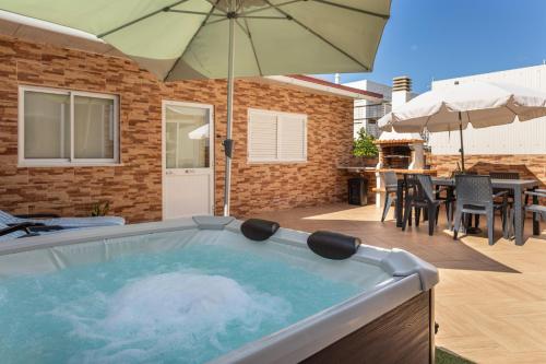 a hot tub with an umbrella on a patio at Zurrinha holidays whit jacuzzi in Quarteira