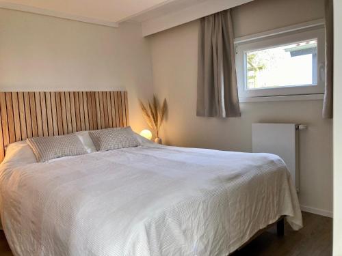a bedroom with a large white bed with a window at 4 pers house Cecil with own fishing spot on a dutch chanel in Anjum