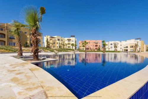 una piscina con una palma e edifici di El-Gouna Water-Side Apartment a Hurghada