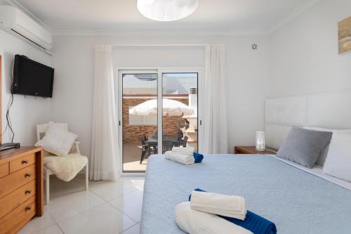 a bedroom with a bed and a television and a chair at Zurrinha holidays in Quarteira