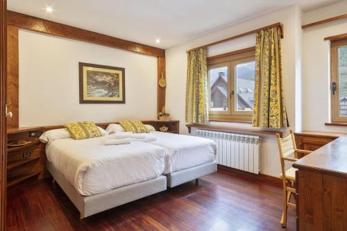 1 dormitorio con cama, escritorio y ventana en Luderna - Apartamento Tuca en Vielha