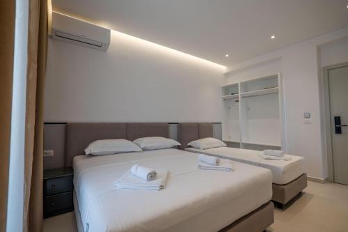 two beds in a hotel room with white sheets at Hotel Emblem in Sarandë