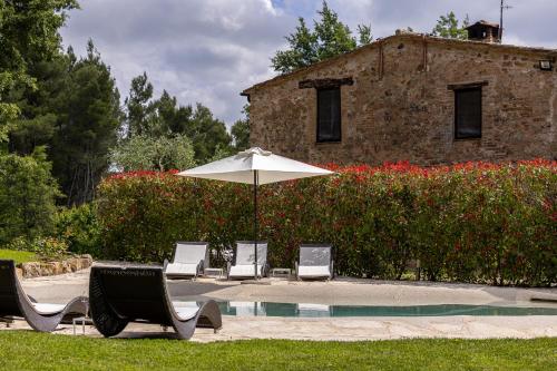 a group of chairs and an umbrella next to a pool at Pietraio in Radicondoli