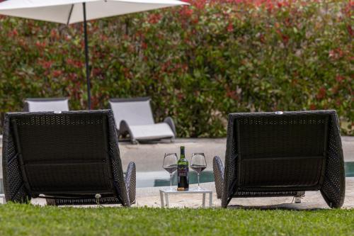 two chairs and a table with wine glasses and an umbrella at Pietraio in Radicondoli