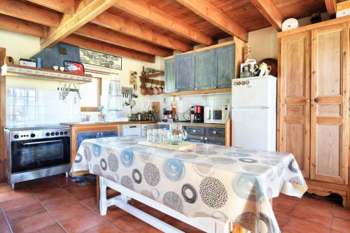 une cuisine avec une table et un réfrigérateur blanc dans l'établissement La Forge de Denn - Ancienne forge pour 6 voyageurs, à Portbail
