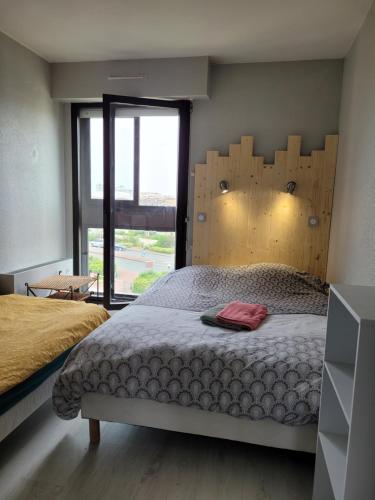 une chambre avec un lit et une grande fenêtre dans l'établissement Appartement à côté de la plage, à La Rochelle
