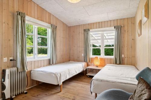 two beds in a room with two windows at Spacious Summer House With Pool in Vejby