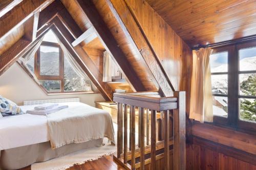 um quarto no sótão com uma cama e uma janela em Luderna - Casa con terraza Cuylas em Baqueira-Beret