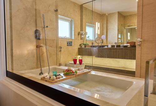 a bathroom with a tub with a shower and two glasses of wine at Shulem Boutique Hotel in Dimāpur