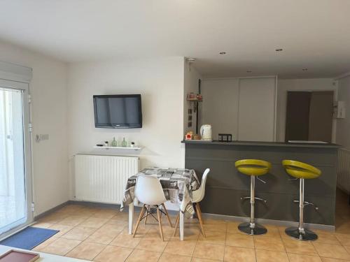 une cuisine avec une table et quelques tabourets jaunes dans l'établissement Joli Studio au calme mais proche gare et bus, à Luzarches