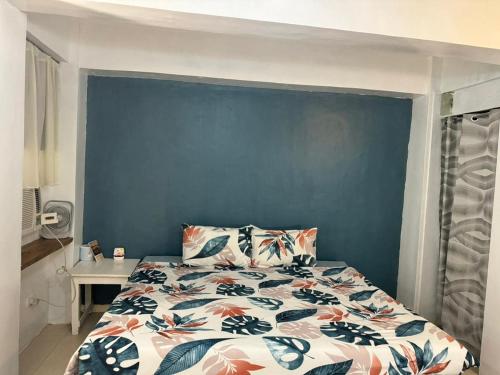 a bedroom with a bed with a blue wall at Paradise Beach Apartment in Boracay