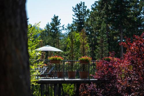 a deck with flowers and an umbrella and a chair at Maxi Park Hotel & Spa in Velingrad