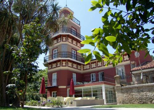 un gran edificio rojo con sillas y sombrillas en Gastro Hotel La Giraldilla, en Liérganes