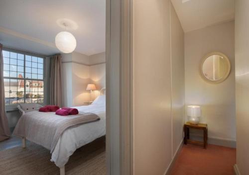 Un dormitorio con una cama con almohadas rosas. en Compass Cottage Shaldon en Shaldon