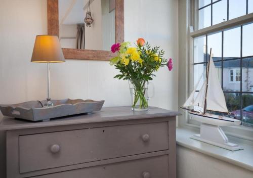un jarrón de flores sentado en un tocador con un barco modelo en Compass Cottage Shaldon en Shaldon