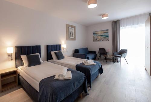 ドンプキにあるSrebrna Wydma Resortのベッド2台とソファが備わるホテルルームです。