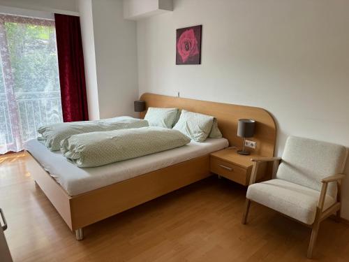 sypialnia z łóżkiem, krzesłem i oknem w obiekcie Lindenhof Deutsch w mieście Bad Tatzmannsdorf