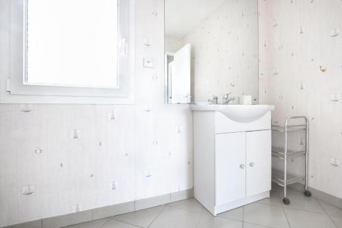 a white bathroom with a sink and a mirror at Un tour dans la Manche - A 500 m de la plage in Portbail