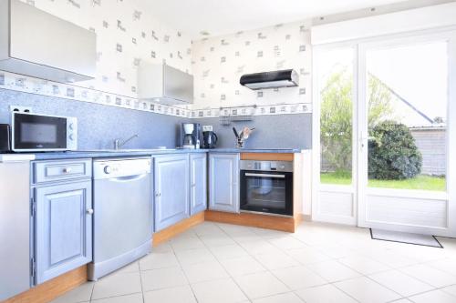une cuisine avec des appareils blancs et une grande fenêtre dans l'établissement Un tour dans la Manche - A 500 m de la plage, à Portbail