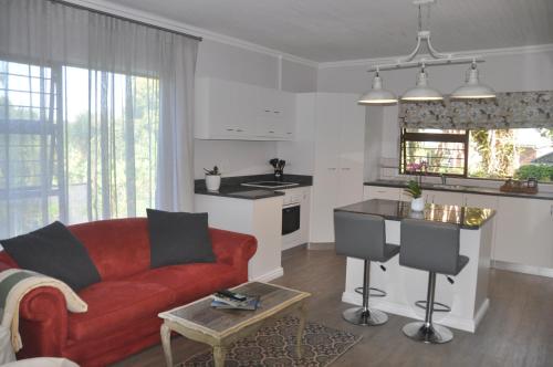 ein Wohnzimmer mit einem roten Sofa und einer Küche in der Unterkunft 62 on Adderley in George