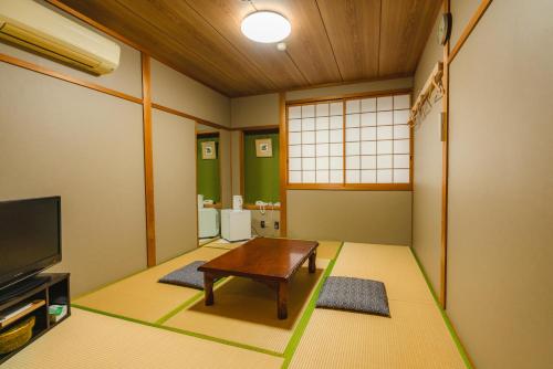 a living room with a table and a tv at Guest House Takiyoshi in Hongu