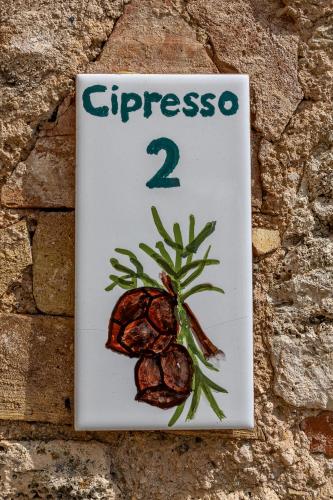 a sign on a stone wall with a sign with a pine branch at Pietraio in Radicondoli