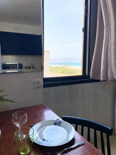 a wooden table with a plate and glasses on it at Apartment on the Mermaid beach in Qiryat Yam