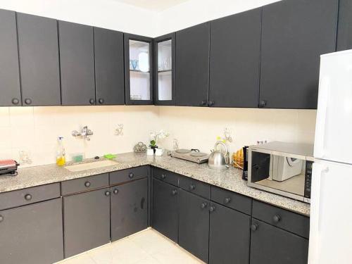 a kitchen with black cabinets and a microwave at Apartment on the Mermaid beach in Qiryat Yam