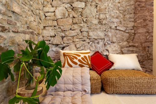 a couch with pillows sitting next to a stone wall at Cal Simon- Casa a Montserrat in Collbató